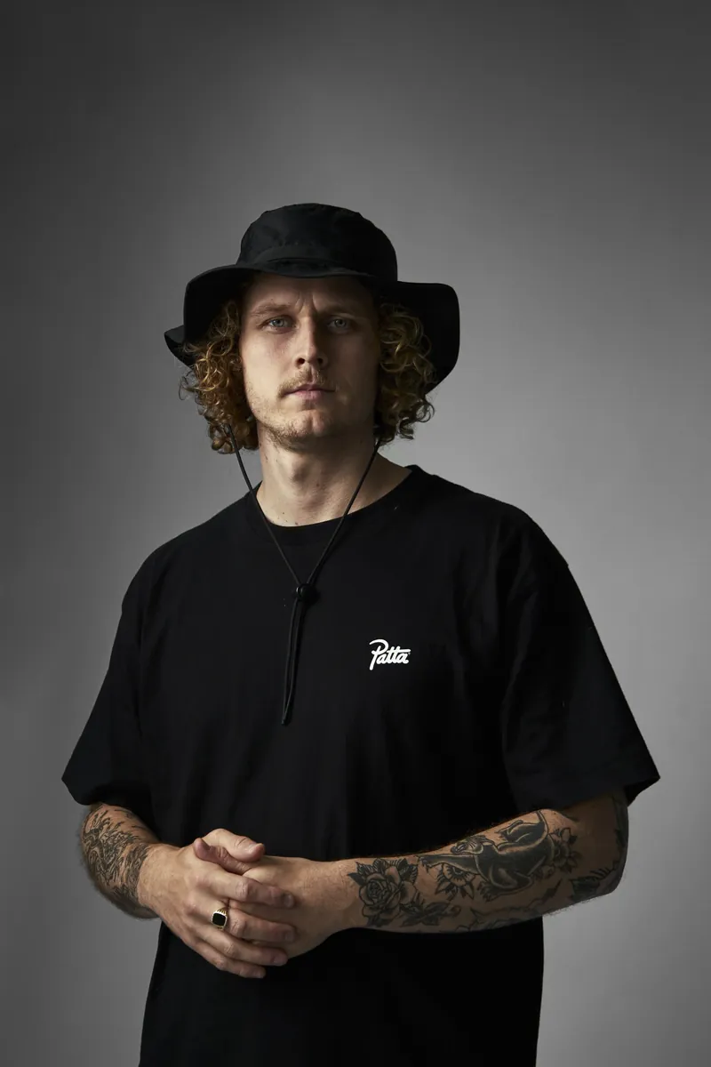 Dj met bucket hat en tatoeages in een zwart shirt