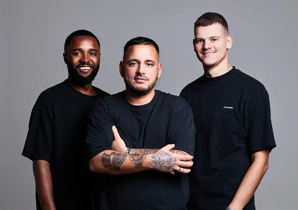 Drie dj's in zwarte shirts tegen een grijze achtergrond